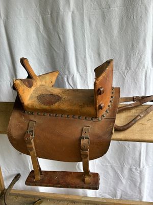 leather horse saddle on a wooden stand against a white backdrop