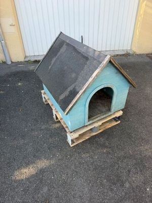 une petite niche pour chien fabriquée à partir de palettes, posée à même le sol