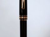 the pen is black and gold with a gold trim around it