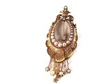 une image représentant une broche en or ornée de perles