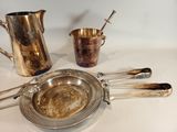 a silver plate with spoons and a silver pitcher on the table