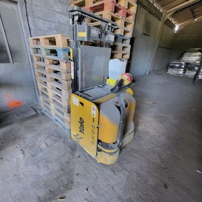 un chariot élévateur dans un entrepôt avec des palettes à l'arrière-plan