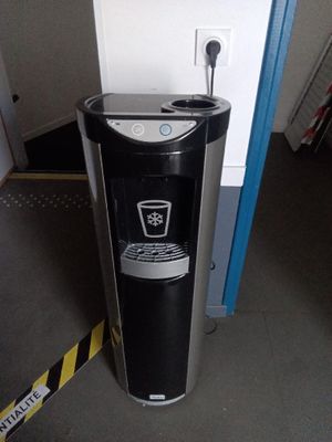 un distributeur d'eau noir et argenté dans un coin de la pièce