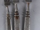 three forks and a knife are sitting on a white surface