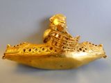 a gold figurine of a man in a boat on a table
