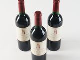 three bottles of red wine sitting on top of a white table