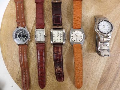 several different watches are sitting on a wooden surface