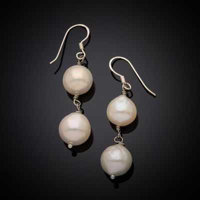 a pair of white pearls and silver earrings on a black background