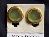 two pairs of green glass stud earrings sitting on top of a white cloth