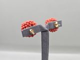 a pair of red beaded earrings on a black stand