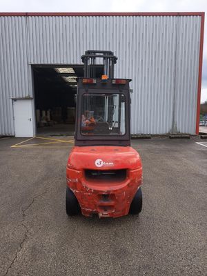 un chariot élévateur rouge garé devant un immeuble