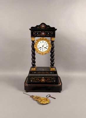 a black and gold clock sitting on a table next to a pair of scissors