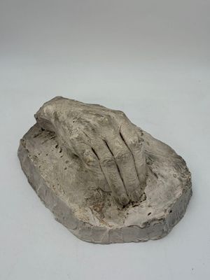 a sculpture of a hand on a rock on a white surface