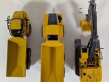 four toy construction vehicles that are sitting on a white surface