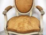 an old chair with a gold upholstered seat and a wooden frame