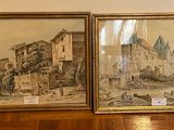 two framed paintings of a castle on a wooden floor next to a wall