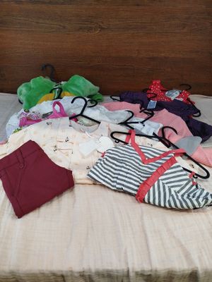 a lot of clothes on a bed with a wooden headboard