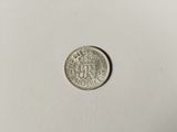 a silver coin with a crown on it sitting on top of a white surface