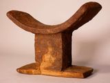 a small wooden sculpture of a curved object on a stand