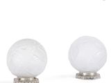 trois lampes en verre blanc posées sur un pied en métal, sur une surface blanche
