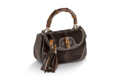 un sac à main en cuir marron muni d'une anse en bambou et de pompons
