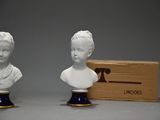 pair of porcelain busts of women with a wooden box in the background