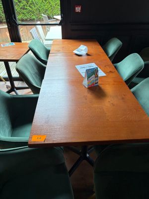 une table en bois avec des chaises vertes et un livre posé dessus