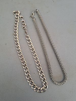 two silver chains are laying on a table next to each other
