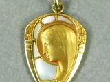 une image représentant un pendentif plaqué or sur lequel figurent une mère et son enfant