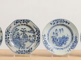 four blue and white plates sitting on top of a wooden table