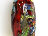a red vase with birds on it on a white surface