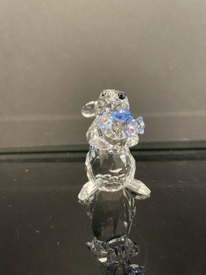 une figurine en verre représentant un lapin tenant une fleur dans la bouche