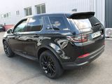 the rear end of a black land rover parked in front of a building