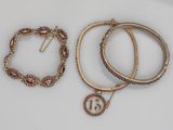 trois bracelets et un collier sont posés sur une surface blanche