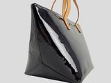 a black handbag with a brown strap hanging from it ' s handle