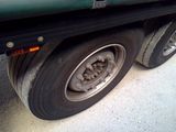a green truck with a flat tire on the street
