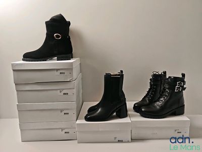 trois paires de bottes noires posées sur une pile de cartons blancs