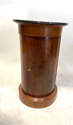 une petite table en bois avec un plateau en marbre, posée sur un plan de travail blanc
