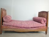 un lit recouvert d'une couverture rose, dans un coin de la pièce