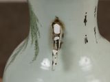 a white vase with a rusted handle sitting on a table