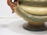 a large vase with a handle on a pedestal