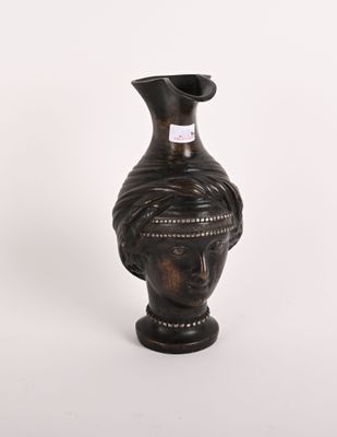 un vase orné d'une tête, posé sur un fond blanc
