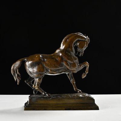 statue en bronze représentant un cheval, posée sur un socle en bois, sur fond noir