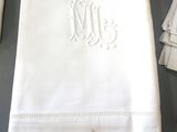 a white napkin with a monogram on it next to a pair of scissors