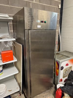 a stainless steel refrigerator next to a stack of shelves