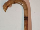 a wooden cane with a curved handle on a white wall