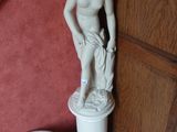 une statue représentant une femme debout sur un socle, à côté de toilettes