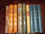 several old books are lined up in a row on a table