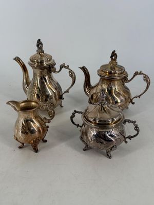 three pieces of silver tea and coffee set on a white surface