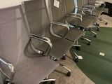 Plusieurs chaises de bureau sont alignées en rangée dans une salle de réunion